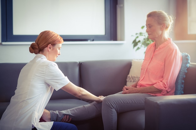 Krankenschwester, die der Frau Beinmassage gibt