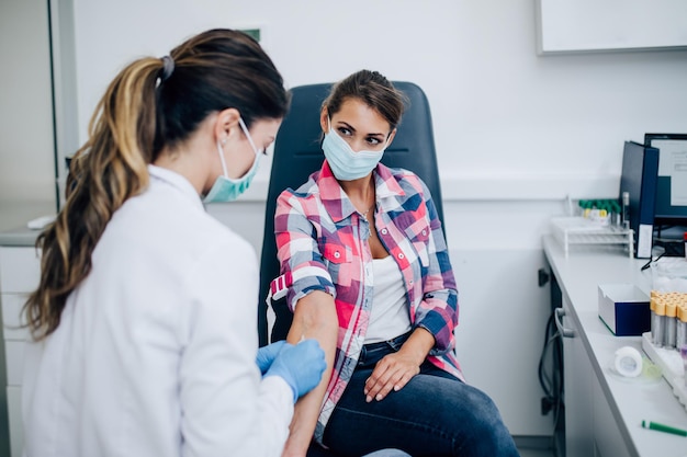 Krankenschwester, die einer jungen Patientin Blutprobe entnimmt.