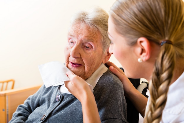 Foto krankenschwester, die mund der älteren frau im pflegeheim abwischt