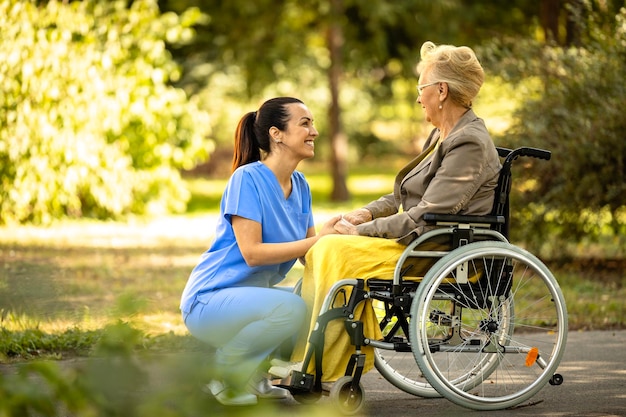 Krankenschwester, die sich um eine ältere Frau im Rollstuhl kümmert