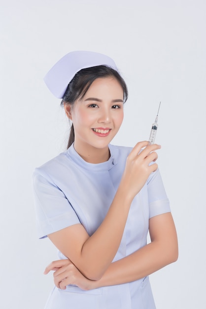 Krankenschwester, die spritze auf weißem hintergrund, asiatische frau trägt
