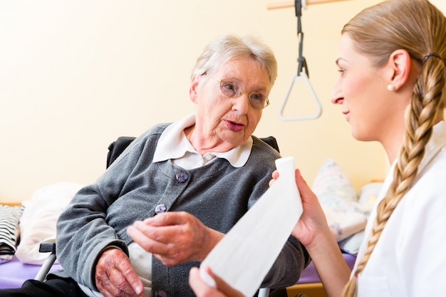 Krankenschwester, die um älterer Frau im Ruhesitz sich kümmert