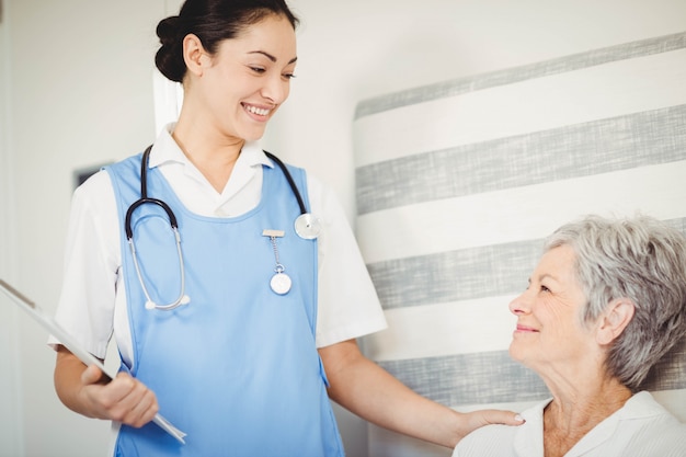 Krankenschwester, die um kranker älterer Frau im Schlafzimmer sich kümmert