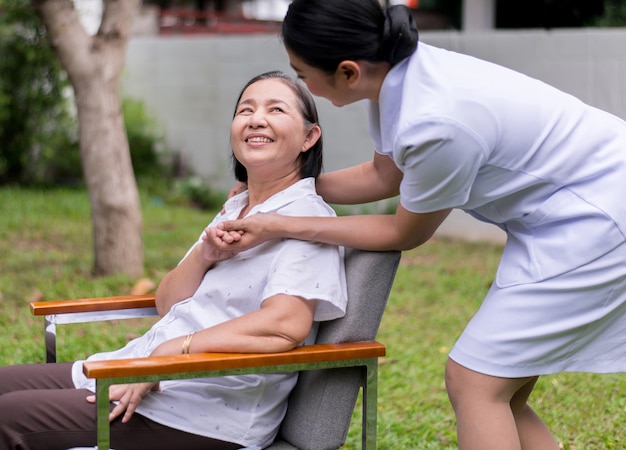 Krankenschwester Händchenhalten an ältere asiatische Frau mit Alzheimer-Krankheit, positives Denken, glücklich und lächelnd, Pflege- und Unterstützungskonzept