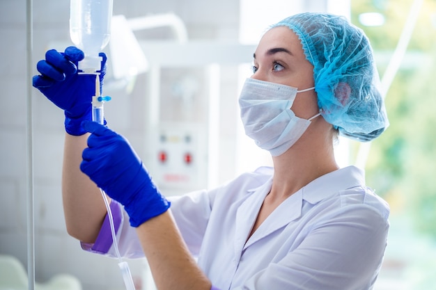 Krankenschwester in medizinischer uniform, die einem patienten einen tropfenzähler für den eingriff im krankenhaus vorbereitet