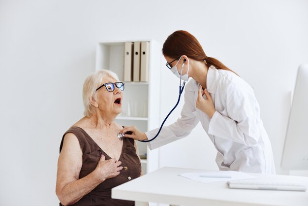 Krankenschwester in weißem Mantel, Stethoskopuntersuchung, Krankenhausbüro, Foto in hoher Qualität