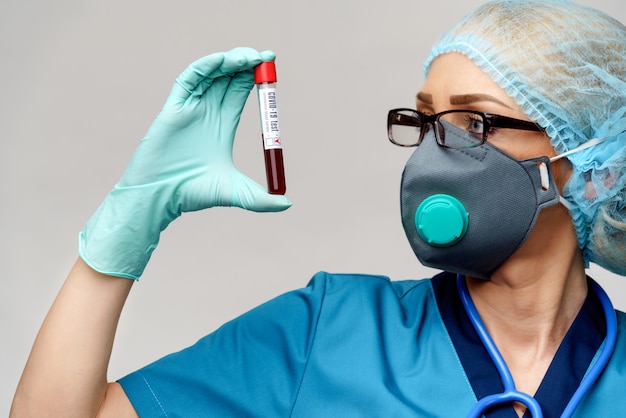 Krankenschwester mit Schutzmaske und Handschuhen und positivem Coronavirus COVID-19-Bluttest
