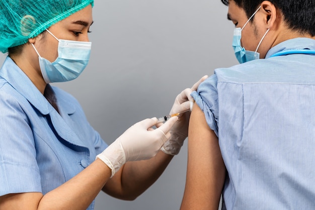 Foto krankenschwester oder medizinisches fachpersonal, das eine spritze hält und baumwolle verwendet, bevor es in eine maske in den ortor injiziert wird. covid-19- oder coronavirus-impfstoff