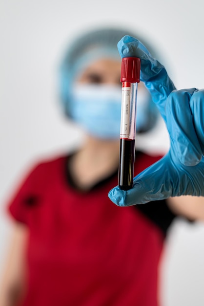 Krankenschwester trägt rote Uniform und hält ein Reagenzglas isoliert auf weißem Hintergrund. Konzept der Covid-19-Epidemie