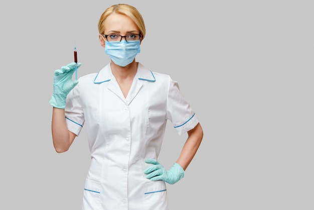 Krankenschwester trägt Schutzmaske mit Spritze