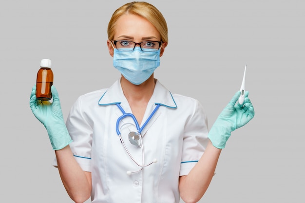 Krankenschwester trägt Schutzmaske und Latexhandschuhe und hält Dose mit Medizin und Thermometer