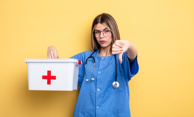 Krankenschwesterfrau, die das Gefühl hat, das Konzept des Erste-Hilfe-Kits mit dem Daumen nach unten zu zeigen