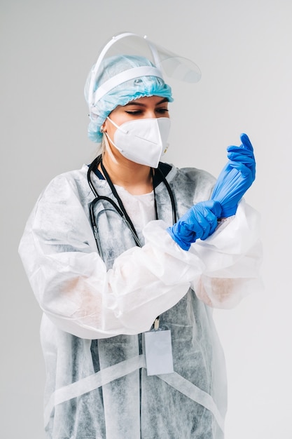 Krankenschwesterkrankenhausarbeiter der jungen Frau in der medizinischen Schutzmaske, in den Handschuhen und in der Schutzkleidung lokalisiert auf weißem Hintergrund.