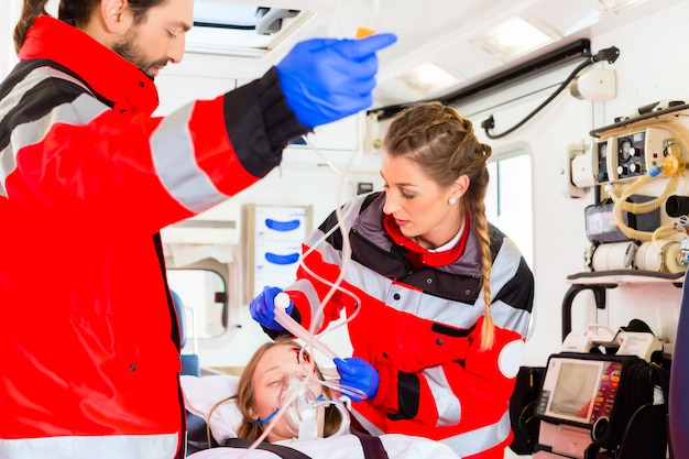 Foto krankenwagen, der verletzter frau auf bahre hilft