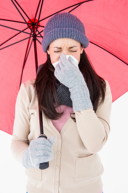 Kranker Brunette, der ihre Nase beim Halten eines Regenschirmes durchbrennt