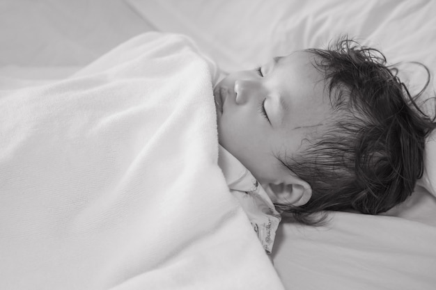 Kranker Kinderschlaf der Nahaufnahme auf Krankenhausbett maserte Hintergrund im Schwarzweiss-Ton
