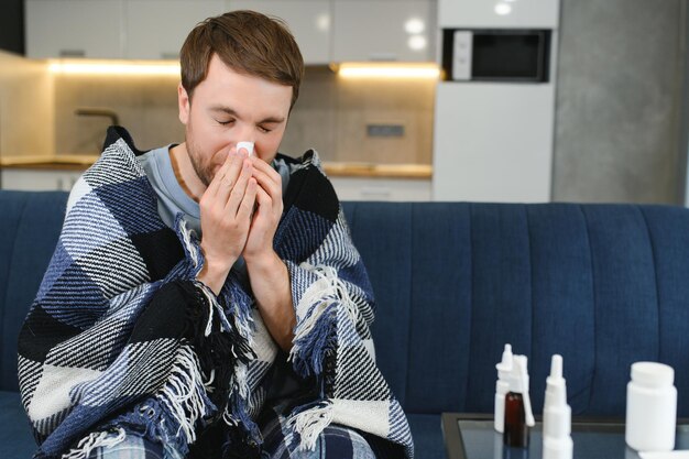 Foto kranker mann auf dem sofa zu hause im wohnzimmer mann fühlt sich krank mit erkältung und fieber zu hause krank mit grippe krankheit sitzt auf dem sofa es ist die saison der niesen