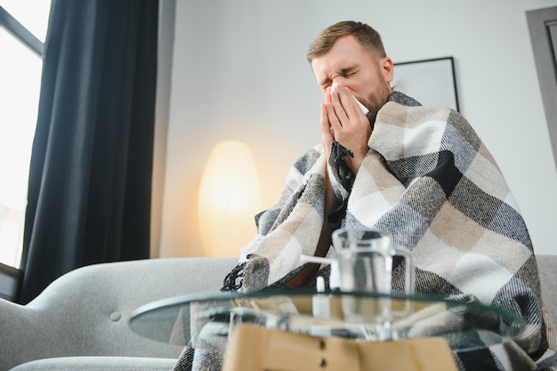 Kranker Mann auf dem Sofa zu Hause und Nase weht