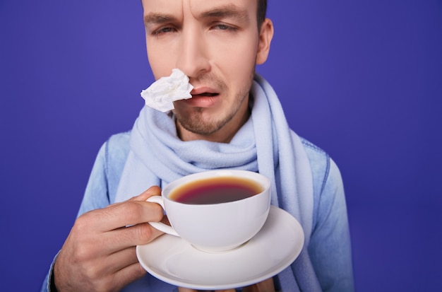 Kranker Mann mit Anti-Influenza-Tee in Händen