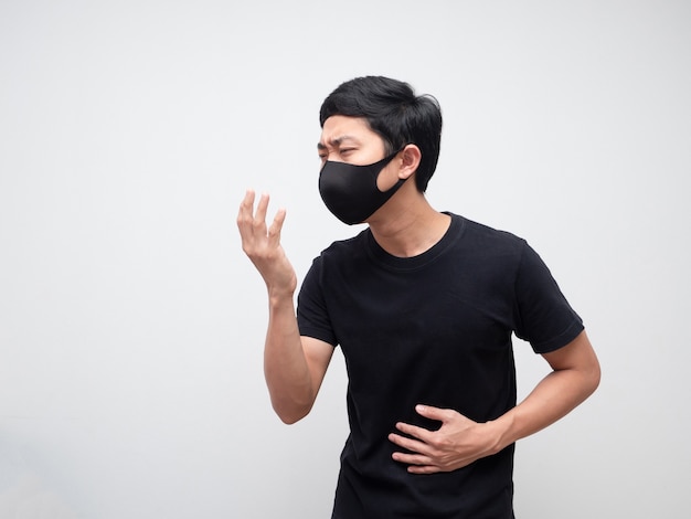 Kranker Mann mit Maske schwarzes Hemd Husten auf weißem isoliertem Raum