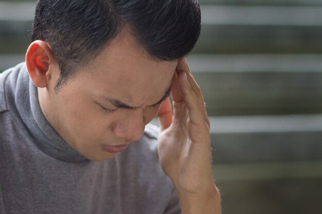 Kranker südostasiatischer Mann mit Kopfschmerzen, Depressionen, Stress