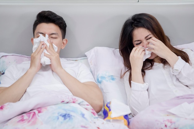 Foto krankes asiatisches paar leidet an grippe auf dem bett