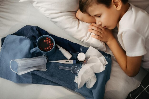 Krankes Kind schläft auf einem Bett in der Nähe gibt es Tablett mit Medikamenten Obstgetränke medizinische Maske