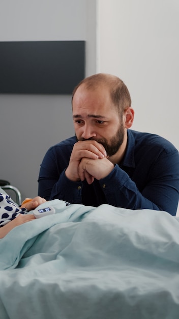 Krankes Kind Tochter trägt Sauerstoff-Nasenröhrchen und Oximeter am Finger, der den Herzschlagpuls überwacht