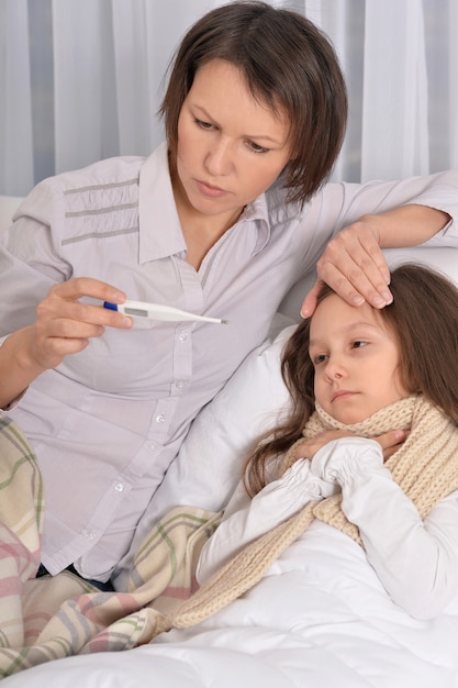 Krankes kleines Mädchen mit Mutter im Bett zu Hause