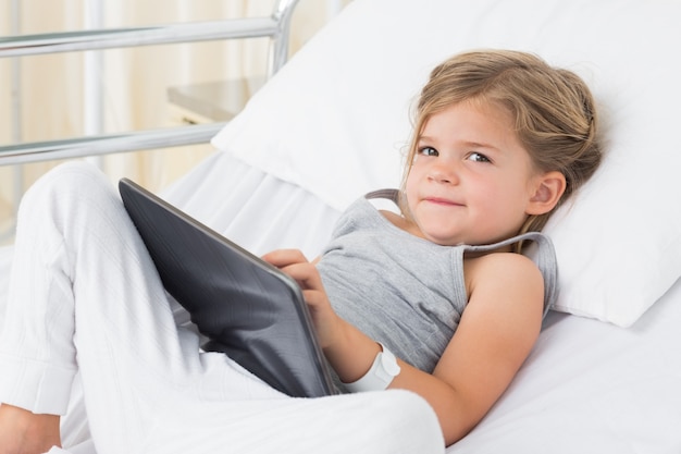 Krankes Mädchen mit digitaler Tablette im Krankenhausbett