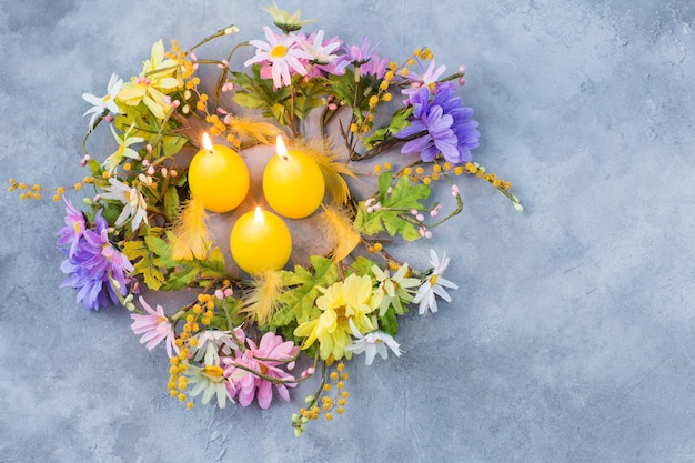 Kranz aus Frühlingsblumen und Mimosen und drei Kerzen