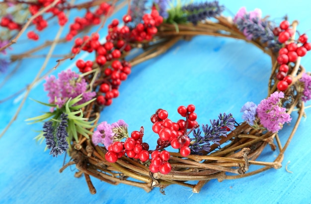 Kranz aus trockenen Ästen mit Blumen und Viburnum auf Holztisch in der Nähe