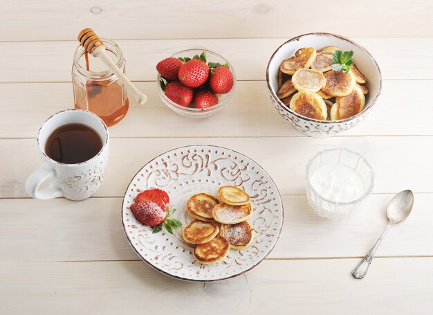 Krapfen mit Sauerrahm und Erdbeeren, Teebecher, Honig mit einem Stück Honig