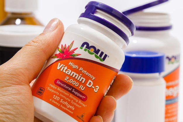 Krasnodar Federación Rusa 10 de diciembre de 2021 Botella de vitamina D3 por NOW en la mano de una mujer Imagen