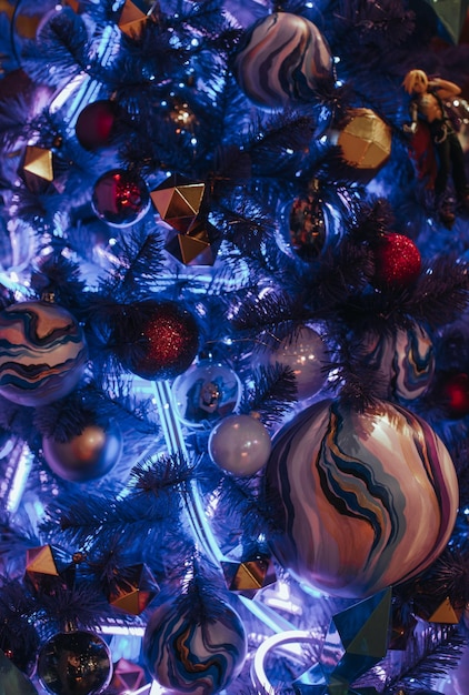Kreativ dekorierter blauer Weihnachtsbaum mit handbemalten Weihnachtskugeln und festlichen Lichtern