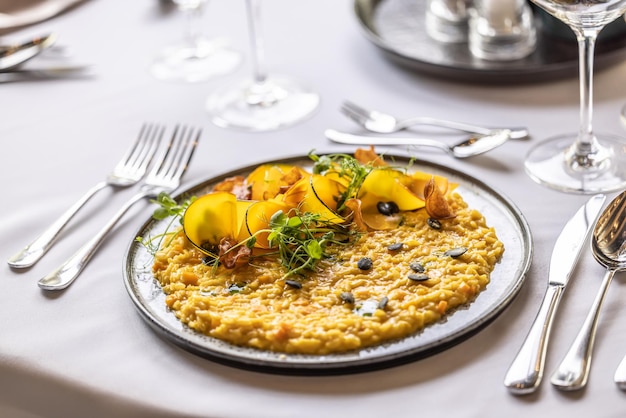 Kreativ gekochtes Kürbisrisotto, serviert auf einem feierlich gedeckten Tisch im Hotelrestaurant