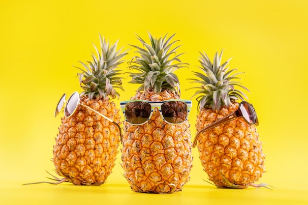 Kreative Ananas mit Sonnenbrille und Schale isoliert auf gelbem Hintergrund Sommerurlaub Strandidee Designmuster Kopierraum Nahaufnahme