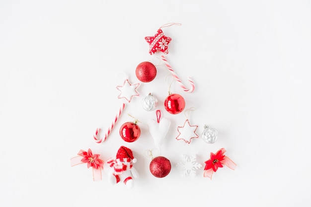 Kreative Anordnung des leuchtend roten Weihnachtsbaums gemacht von Weihnachtsball, Süßigkeiten, Spielzeug auf weißem Hintergrund.