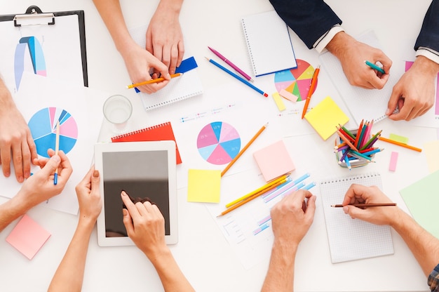 Kreative Arbeit. Draufsicht auf Geschäftsleute, die zusammenarbeiten, während sie am Tisch sitzen