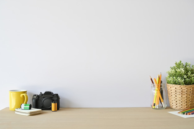 Kreative Arbeitsplatzkamera und Büroartikel auf hölzernem Schreibtisch mit Kopienraum.