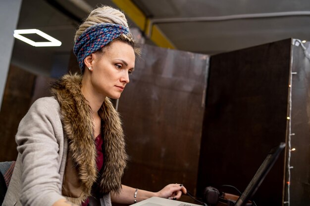 Kreative Frau, die am Schreibtisch in ihrem modernen Bürointerieur arbeitet, während sie auf den Computerbildschirm schaut Programmentwicklungskonzept