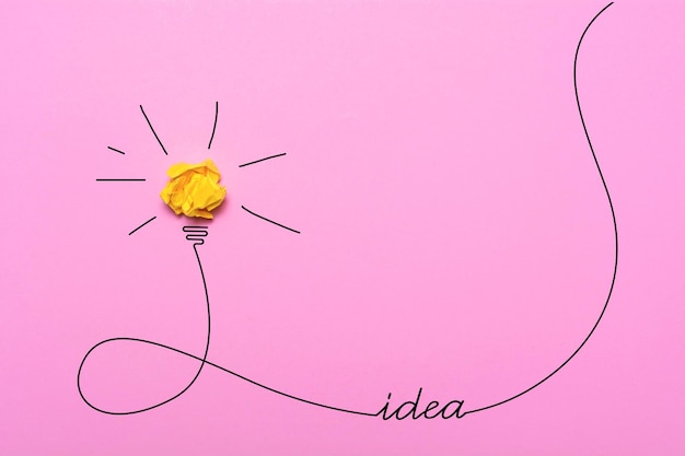 Kreative Idee aus zerknittertem Papier Eine brennende Glühbirne auf rosafarbenem Hintergrund