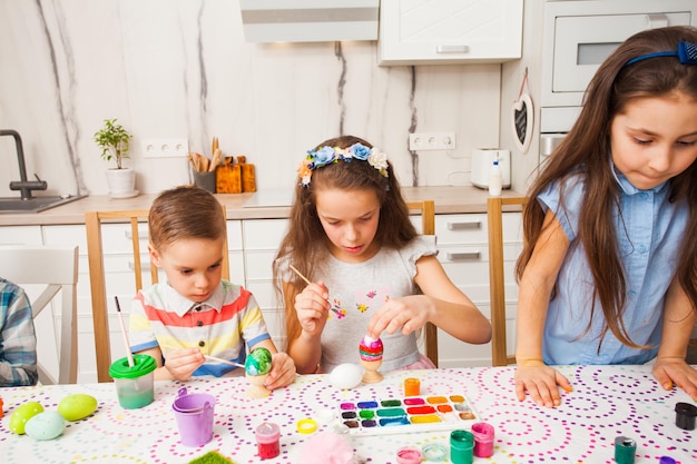 Kreative Kinder malen Eier. Glückliche Familie bereitet sich auf Ostern vor.