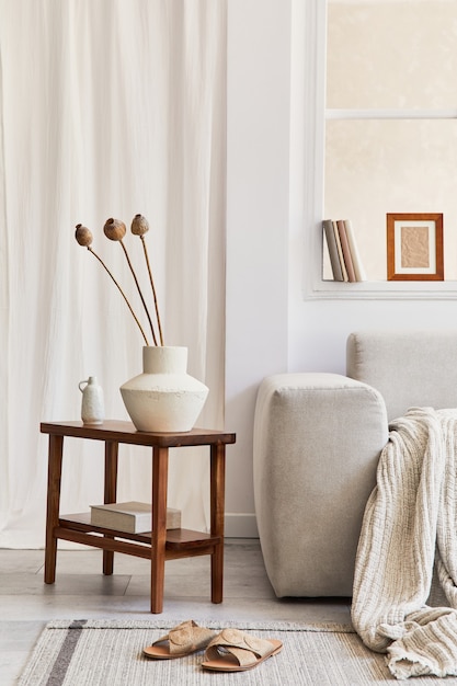 Kreative Komposition aus stilvollem und gemütlichem Wohnzimmer mit Mock-up-Rahmen, grauem Ecksofa, Fenster, getrockneten Blumen auf dem Couchtisch und persönlichen Accessoires. Beige neutrale Farben. Vorlage.