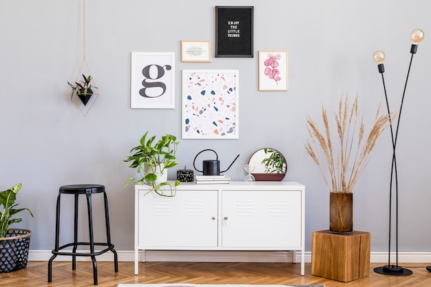 Kreative Komposition aus stilvollem Wohnzimmer mit moderner Innenarchitektur mit Posterrahmen aus Holz-Toilettenstuhl-Kissen-Spiegelpflanzen und Zubehör. Neutrale Wände Parkettboden