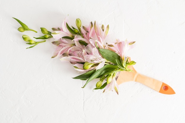 Kreative Komposition mit Blumen und Pinsel Der Frühling ist eine Zeit des Wandels. Malen Sie das Leben mit verschiedenen Farben, weißem Hintergrund