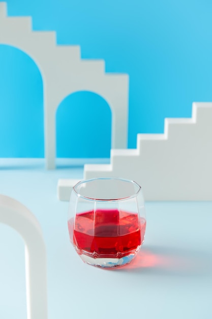 Kreative Komposition mit Cranberry-Limonade-Cocktail im Glas auf blauem Hintergrund