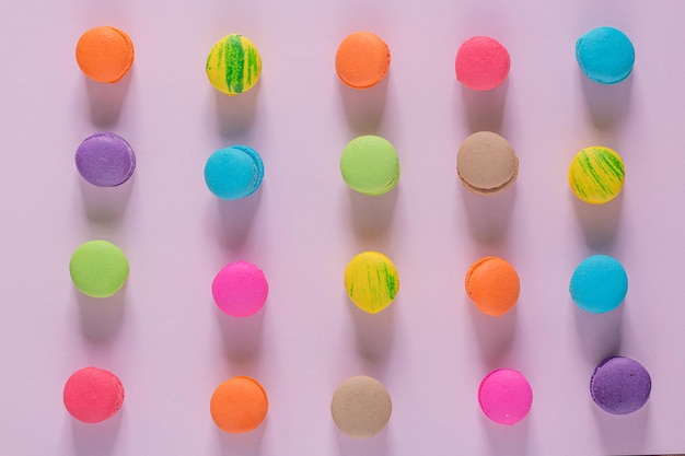 Kreative Komposition mit Umschlag und Kuchen Macaron oder Makrone auf Draufsicht des rosa Pastellhintergrundes.