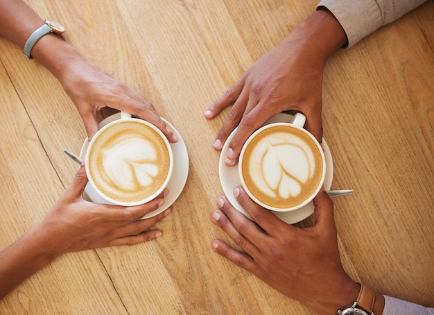 Kreative Latte Art Cappuccino und Kaffeegetränk im Café mit Paar und Freunden, die gemeinsam eine Tasse Java mit Milchschaum genießen Nahaufnahme von Menschenhänden von oben, die sich im Restaurant treffen und trinken