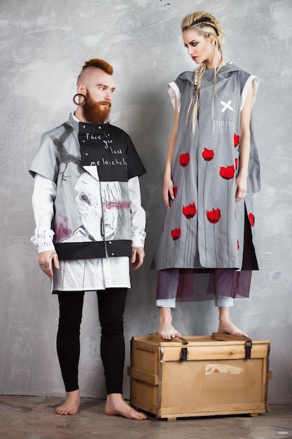 Kreative ungewöhnliche blonde Frau und rothaariger Mann in Designerkleidung